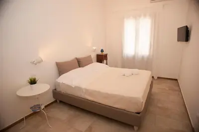a white bedroom with a bed and a table at B&B Nencioli in Castellammare del Golfo