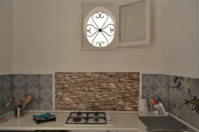 a kitchen with a brick wall and a window at Dietro al Massimo in Palermo