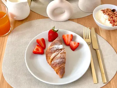 a plate with a croissant and strawberries on a table at Villa di Nera B&B in Palermo