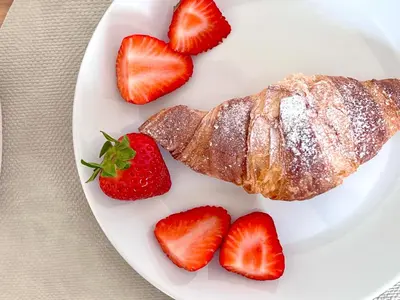 a plate of croissant and strawberries on a table at Villa di Nera B&B in Palermo
