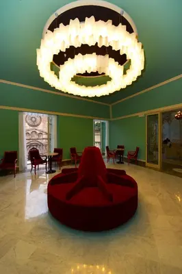 a living room with a red couch and a chandelier at Grand Hotel Piazza Borsa in Palermo