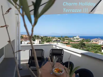 a table and chairs on a balcony with a view of the ocean at Charm Holiday in Terrasini