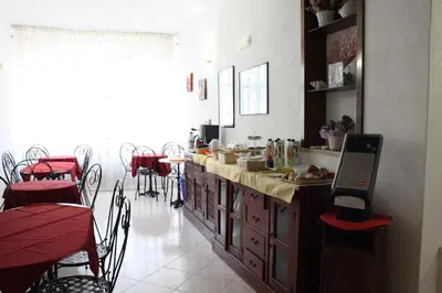 a kitchen with a counter with red tables and chairs at Locanda Lighea Rooms in San Vito lo Capo
