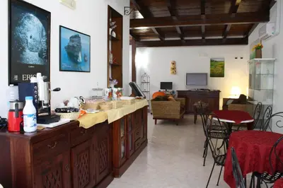 a kitchen with a counter and a living room at Locanda Lighea Rooms in San Vito lo Capo