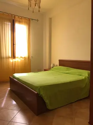 a bedroom with a green bed and a window at Casa Irene in San Vito lo Capo