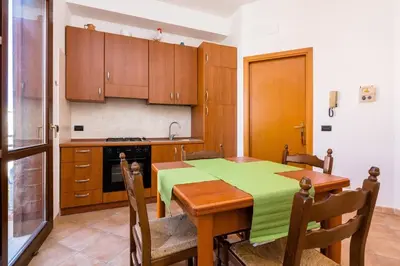 a kitchen with a wooden table with a green table cloth at Casa Irene in San Vito lo Capo