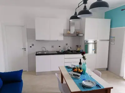a kitchen with white cabinets and a table with fruit on it at Appartamento Il Gabbiano in Balestrate