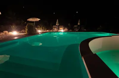 a swimming pool lit up at night at Tenute Plaia Agriturismo in Scopello