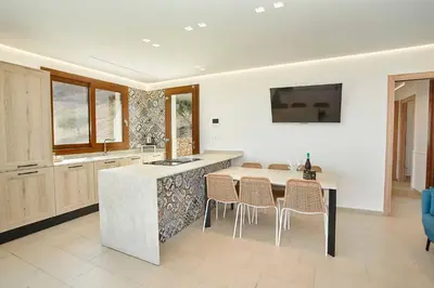 a kitchen with a table and chairs and a sink at Villa dell'Artista in Scopello