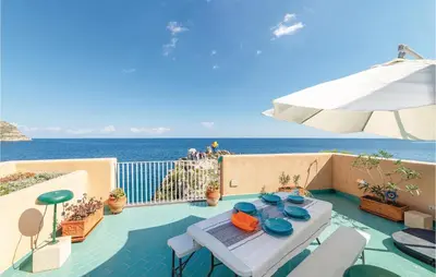 a patio with a table and an umbrella and the ocean at Villa Kericia in Porticello