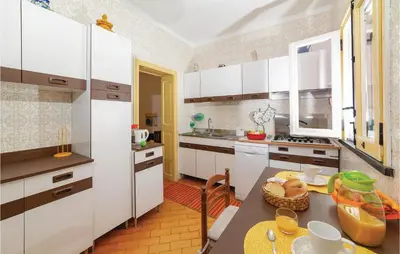 a kitchen with white cabinets and a table at Villa Kericia in Porticello