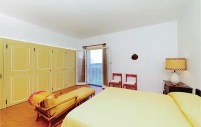 a bedroom with a yellow bed and chairs in it at Villa Kericia in Porticello