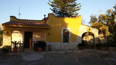 a yellow house with a stone wall at Villa Belvedere Michelle in Trappeto