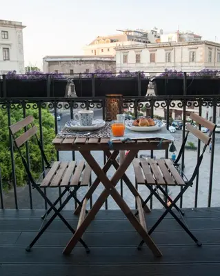 a table with plates of food and two chairs on a balcony at Petrosino in Palermo