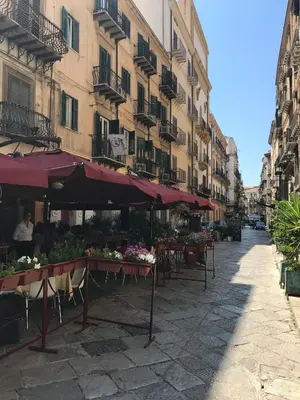 a street with tables with flowers and umbrellas at Petrosino in Palermo