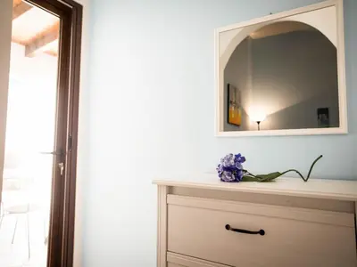 a dresser with a mirror and purple flowers on it at Appartamento gli archi a 100 metri dalla spiaggia in Castellammare del Golfo