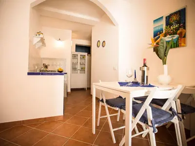 a kitchen and dining room with a white table and chairs at Appartamento gli archi a 100 metri dalla spiaggia in Castellammare del Golfo