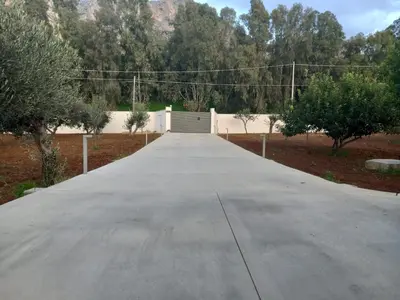 a driveway leading to a garage with a fence and trees at Villa Eagle in Terrasini