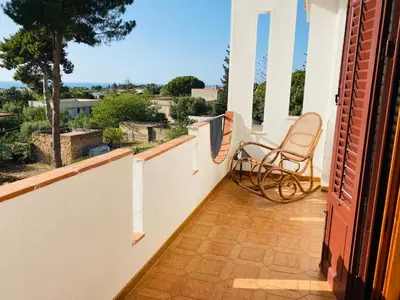 a chair sitting on the balcony of a house at Villa Eagle in Terrasini