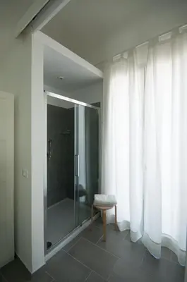 a bathroom with a glass shower and a stool at Dietro il Teatro in Palermo
