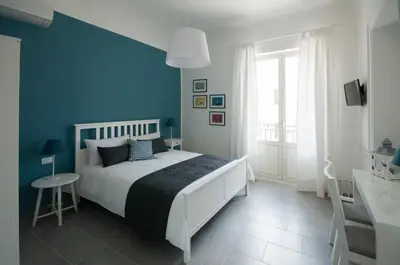 a bedroom with a white bed and a blue wall at Dietro il Teatro in Palermo