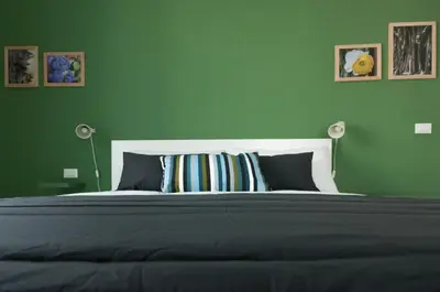 a green bedroom with a large bed with two lamps at Dietro il Teatro in Palermo
