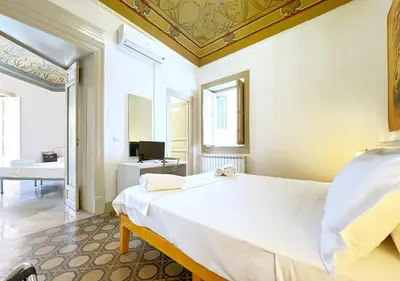 a bedroom with a large white bed and a bathroom at Solemar Sicilia - Monacò rooms in Palermo