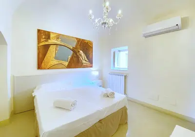 a white room with a bed and a chandelier at Solemar Sicilia - Monacò rooms in Palermo