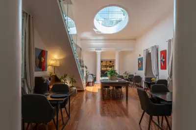 a living room with a table and chairs and a staircase at L' Hôtellerie Easy Suites in Palermo