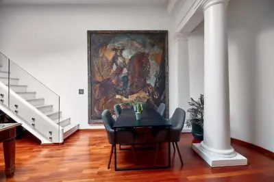 a dining room with a table and a painting on the wall at L' Hôtellerie Easy Suites in Palermo