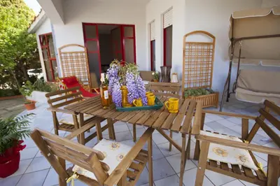 a wooden picnic table with chairs on a patio at Grace's Place in Scopello