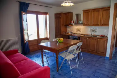 a kitchen with a wooden table and a red couch at Terrazze sul Tirreno in Lascari