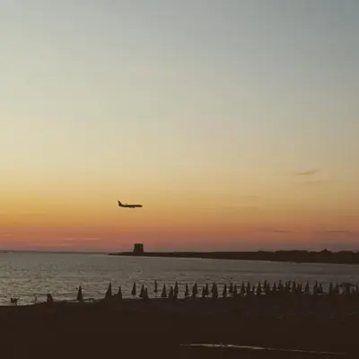 an airplane is flying over the beach at sunset at B&B Cinisi Vacanze 2.0 in Cinisi