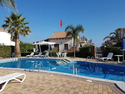 a swimming pool with chairs and a house at Mansarda con Vista Piscina in Campofelice di Roccella