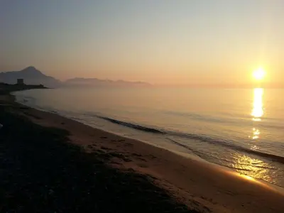 a beach with the sun setting over the water at Mansarda con Vista Piscina in Campofelice di Roccella