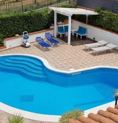 a large blue swimming pool with chairs and a table at Villa Sunshine in Balestrate