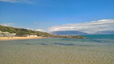 a beach with the ocean and mountains in the background at Villa Sunshine in Balestrate