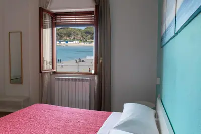 a bedroom with a bed and a view of a beach at Mondello Beach Rooms - by the sea in Mondello