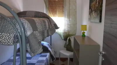 a bedroom with a bed and a desk and a window at Casa Vacanze Reginotte in Balestrate