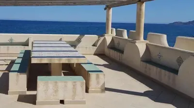 a picnic table on the side of a building with the ocean at Villa Mare Ficarazzi in Ficarazzi