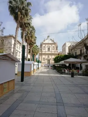 an empty street in front of a building with palm trees at Maui apartament in Alcamo