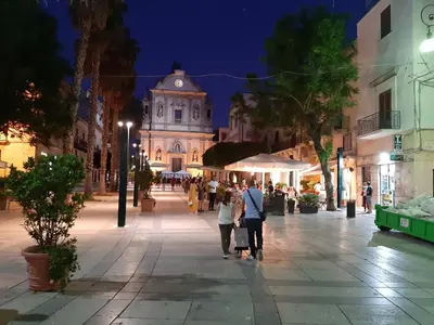 a group of people walking down a street at night at Maui apartament in Alcamo