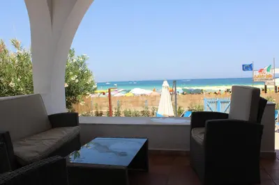 a patio with chairs and a table and a view of the beach at Villa Casa Madre in San Vito lo Capo