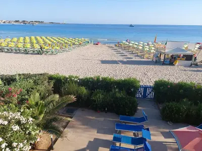 a beach with chairs and umbrellas and the ocean at Villa Casa Madre in San Vito lo Capo