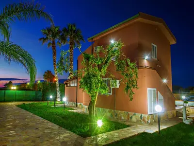 a house with palm trees in front of it at night at Gelso Bianco Apartments in Campofelice di Roccella