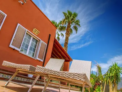 a orange building with a bench next to a palm tree at Gelso Bianco Apartments in Campofelice di Roccella