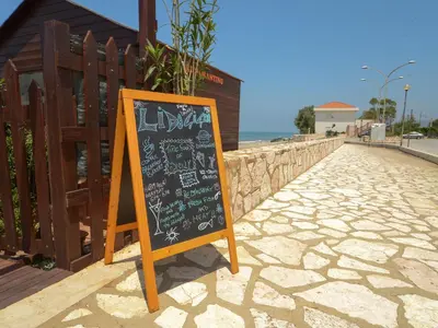 a chalkboard sign on a sidewalk next to a beach at Gelso Bianco Apartments in Campofelice di Roccella
