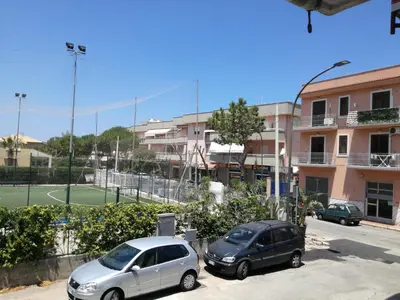 two cars parked in a parking lot next to a tennis court at Sunset Flat in Isola delle Femmine