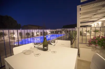 a white table with two wine glasses on a balcony at Villa Del Mare in Alcamo Marina