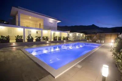 a swimming pool in front of a house at night at Villa Del Mare in Alcamo Marina